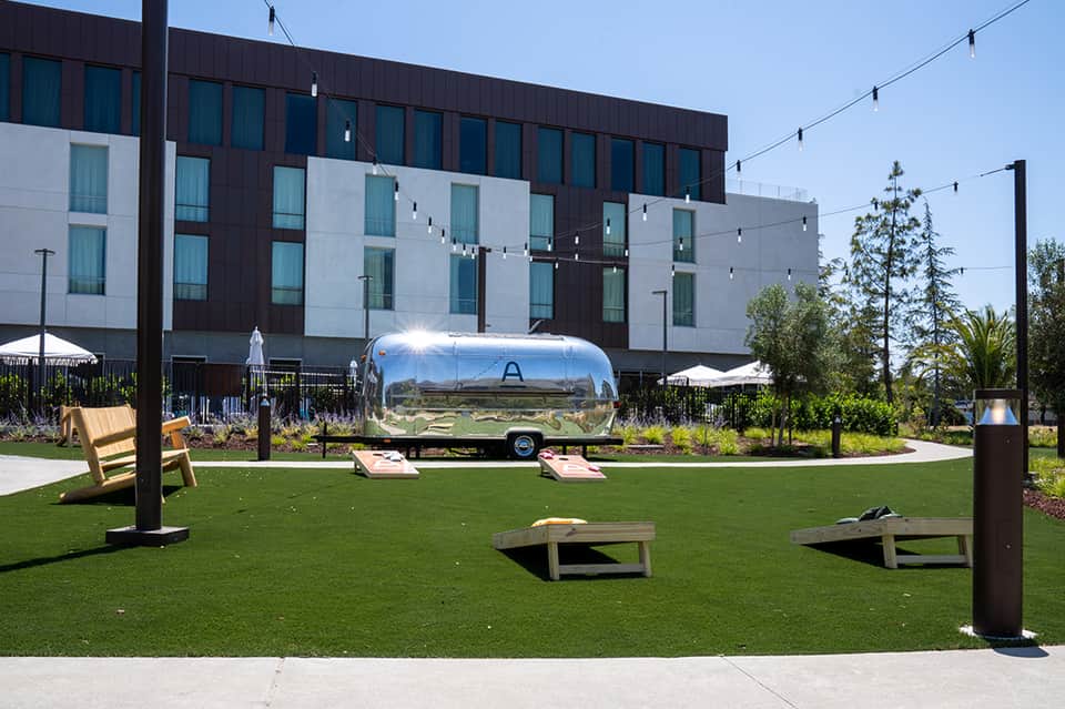 Modern hotel courtyard with Airstream trailer, games, and contemporary architecture