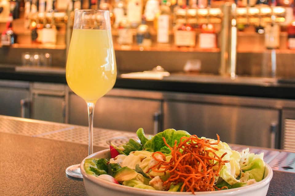 Cocktail and fresh salad served at upscale bar restaurant counter