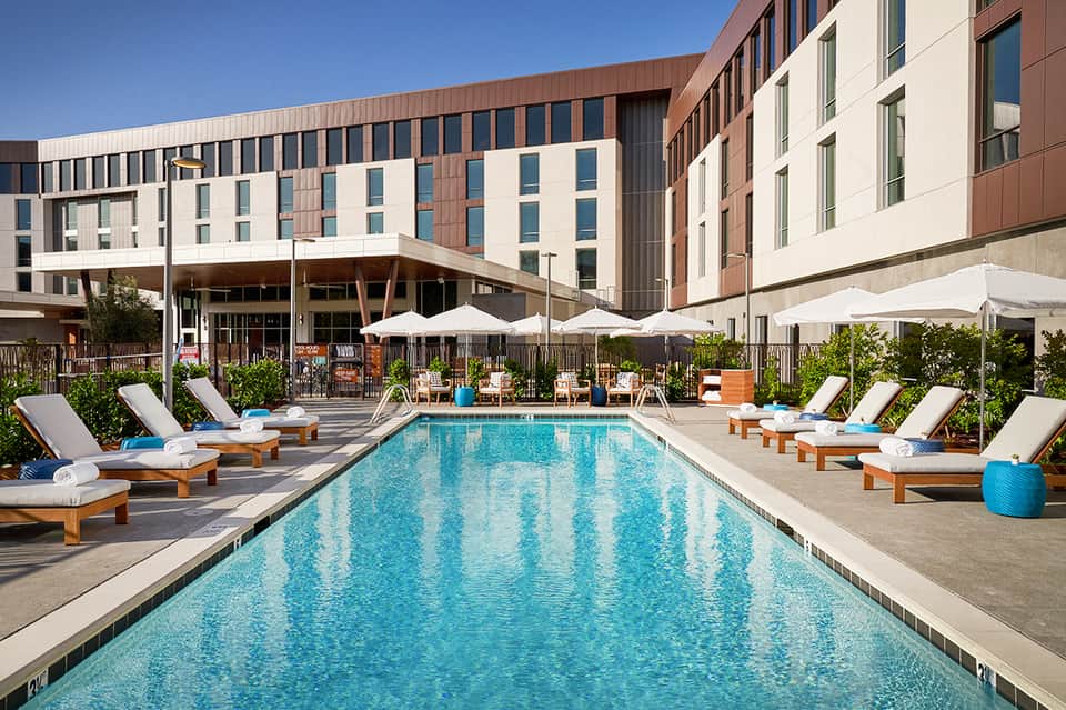 Contemporary hotel pool with wooden loungers and white umbrellas