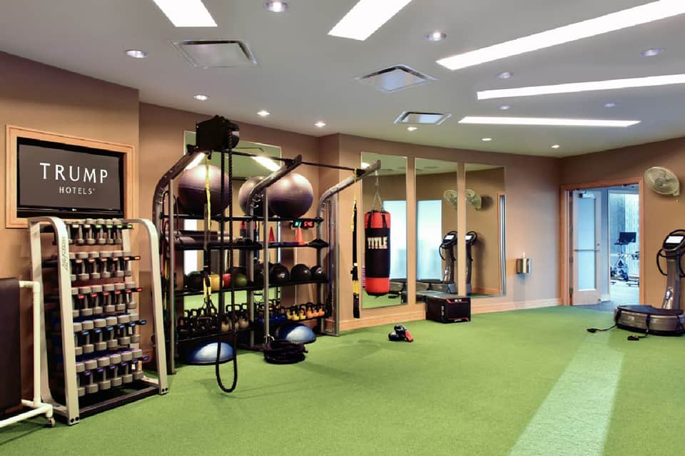 Full-service gym with weight rack, boxing bag, exercise equipment, and mirrored walls