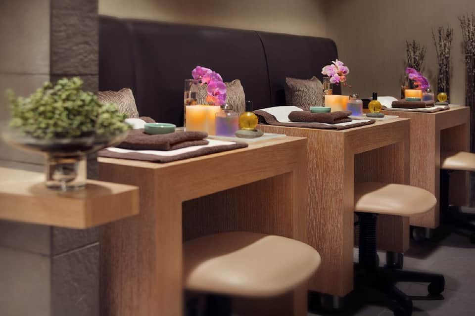 Luxury spa treatment stations with wooden counters, pink orchid flowers, and decorative accessories
