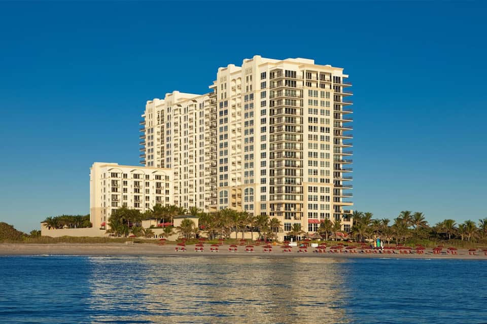 Multi-story beachfront hotel building with cream-colored architecture on sandy beach with ocean view