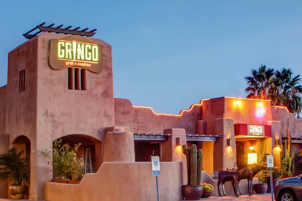 Southwestern-style Gringo restaurant exterior with terracotta walls and palm trees at dusk