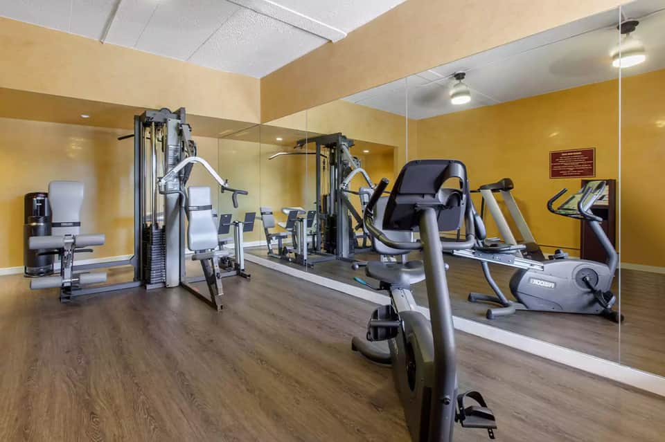 Modern fitness center with yellow walls, cardio equipment, and mirrored walls