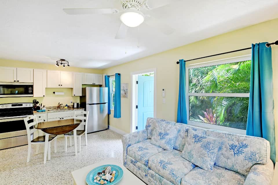 Bright condo interior with yellow walls, white kitchen, blue curtains, and coral pattern sofa
