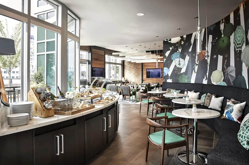 Modern hotel lounge with floor-to-ceiling windows, comfortable seating, and contemporary artwork