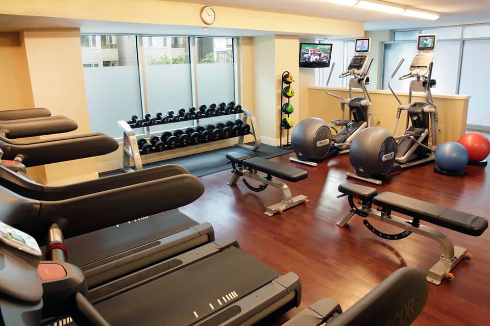 Modern fitness center with cardio equipment, free weights, dumbbells, and exercise machines