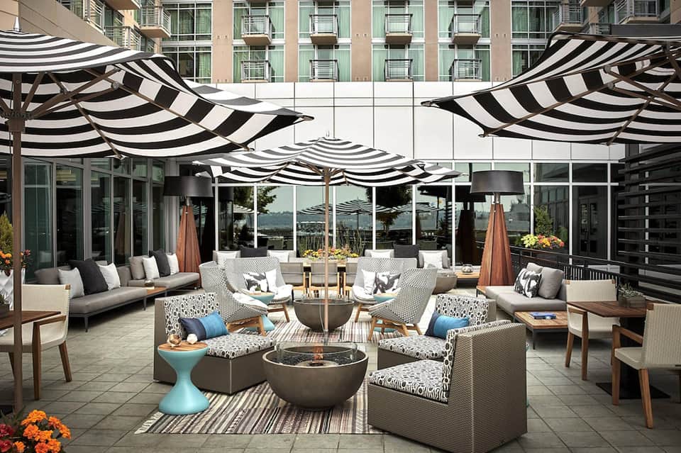 Upscale patio with black and white striped umbrellas, seating, and fire pit