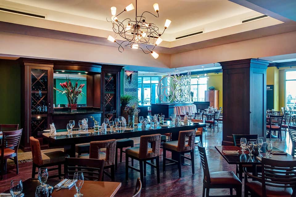 Fine dining restaurant with modern chandelier, elegant table settings, and turquoise accents