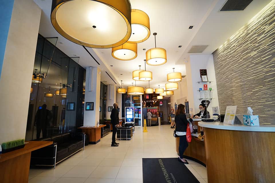 Hotel lobby interior with golden pendant light fixtures, reception desk, and modern architectural design