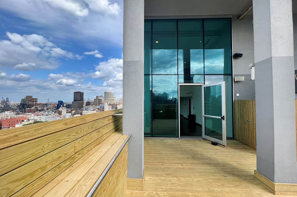 Wooden deck with modern glass doors overlooking a city skyline on a clear day