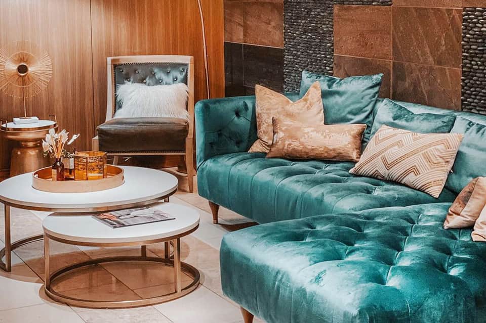 Modern resort lounge with teal velvet sofa, copper accents, and earth-tone pillows