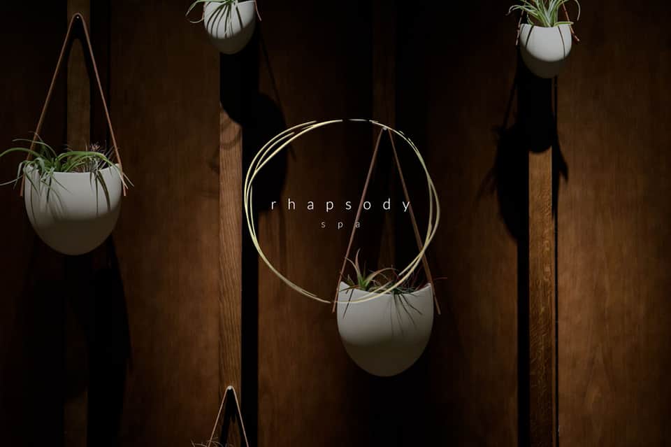 Minimalist spa entrance with hanging white planters and Rhapsody spa signage