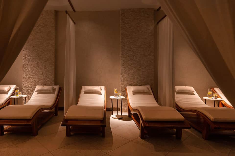 Spa relaxation room with wooden lounge beds and ambient lighting