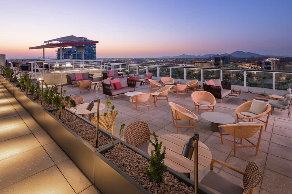 Sunset rooftop terrace with lounge seating, city lights, and mountain views