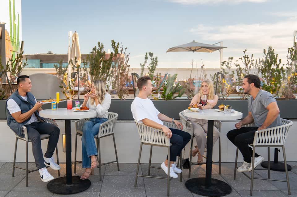 Guests dining on rooftop terrace with city skyline views and modern umbrellas