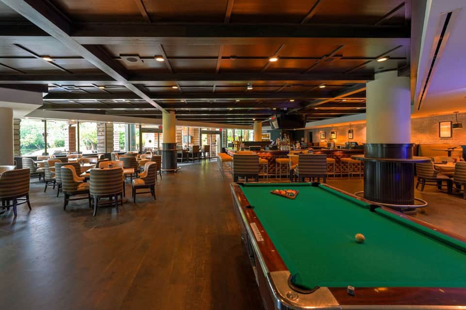 Spacious lounge area with pool table, bar seating, and ambient warm lighting