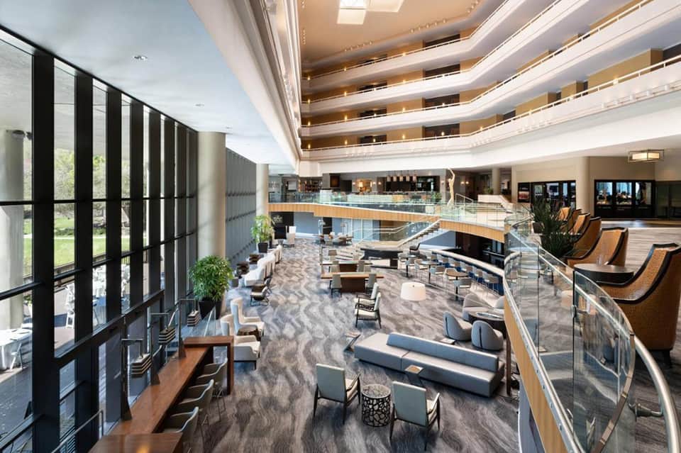 Contemporary hotel lobby atrium with curved balconies, modern seating, and natural lighting