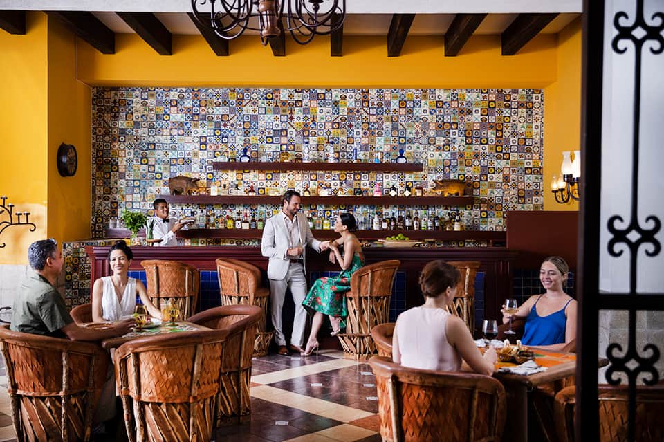Vibrant hotel bar with colorful tile backdrop and guests enjoying cocktails