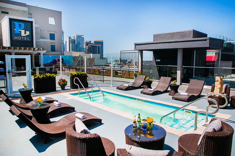 Rooftop pool at urban hotel with city skyline views, lounge chairs, and modern cabana
