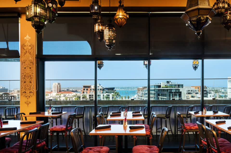 Upscale dining room with panoramic waterfront windows, Moroccan pendant lamps, and ocean city skyline views