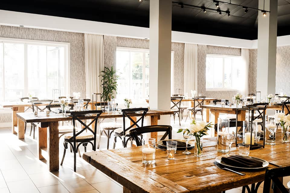 Bright dining room with wooden tables, black chairs, and large windows