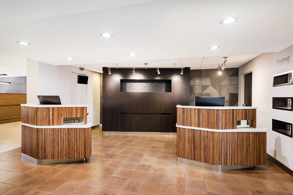 Hotel lobby reception area with curved wooden desks and modern lighting fixtures