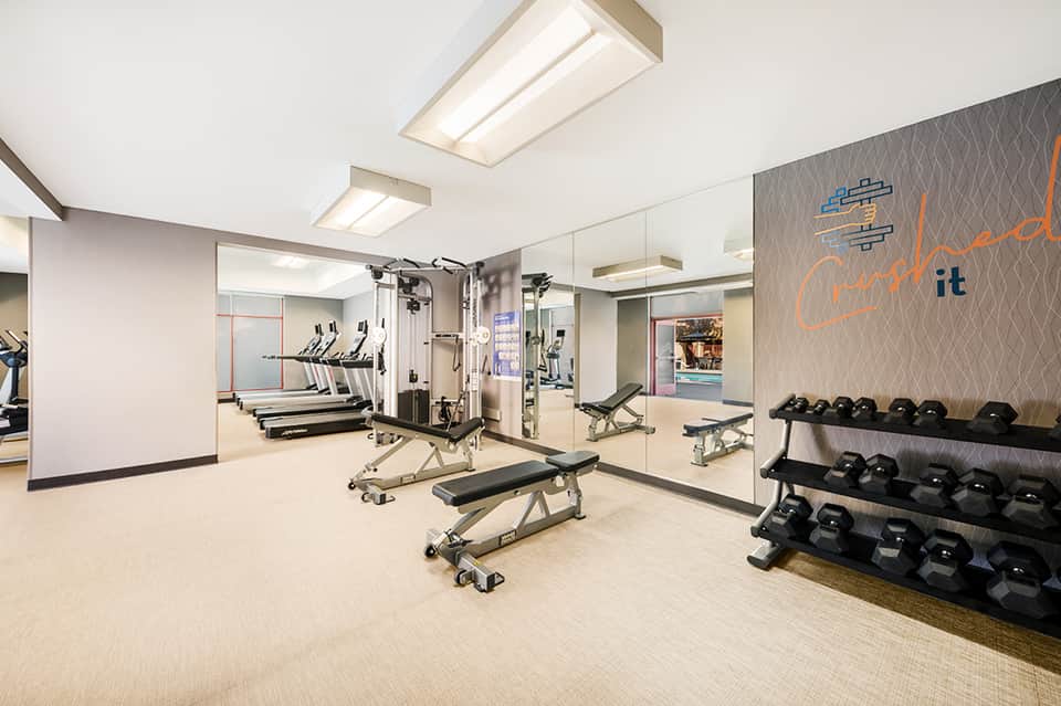 Fitness center with treadmills, weight equipment, mirrors, and motivational wall signage
