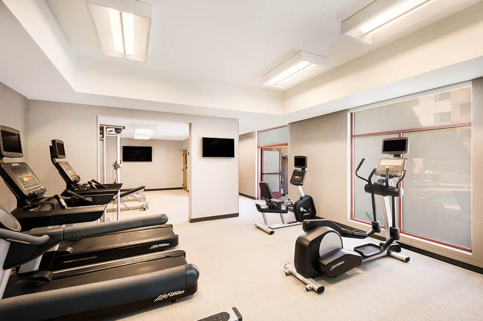 Modern hotel fitness center with treadmills, exercise bikes, and wall-mounted screens