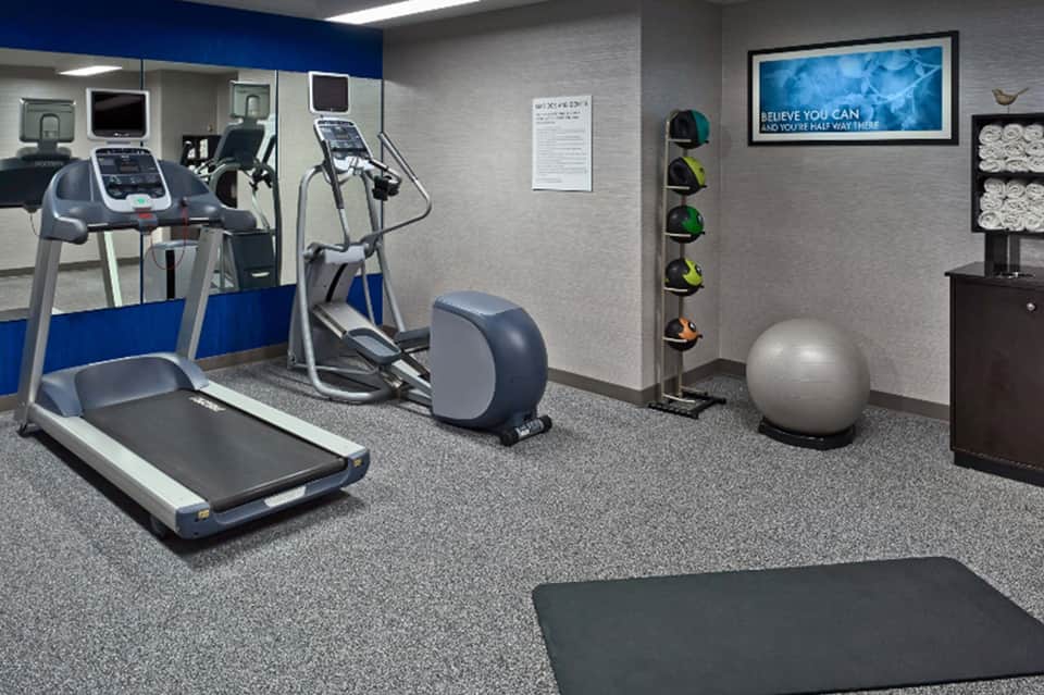 Fitness center with treadmill, elliptical machine, exercise ball, and motivational wall signage