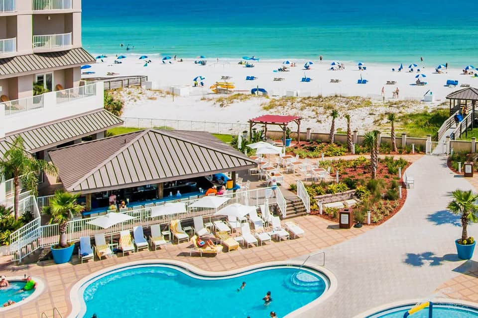 Beachfront resort with pool, lounge chairs, and pristine white sand beach with turquoise ocean