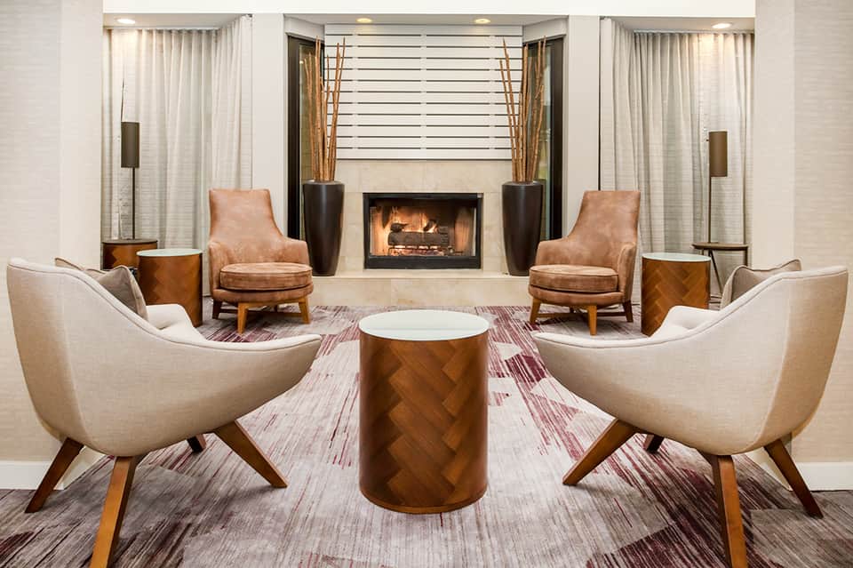 Elegant hotel lobby lounge with fireplace, cream and tan upholstered chairs, and sophisticated décor