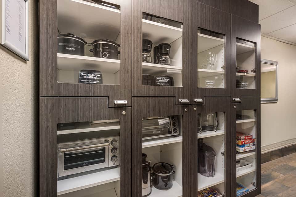 Hotel kitchen equipment storage with glass-front cabinets displaying appliances and kitchenware