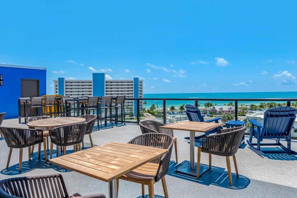 Rooftop terrace with modern furniture, ocean and coastline views, bright blue sky and turquoise water