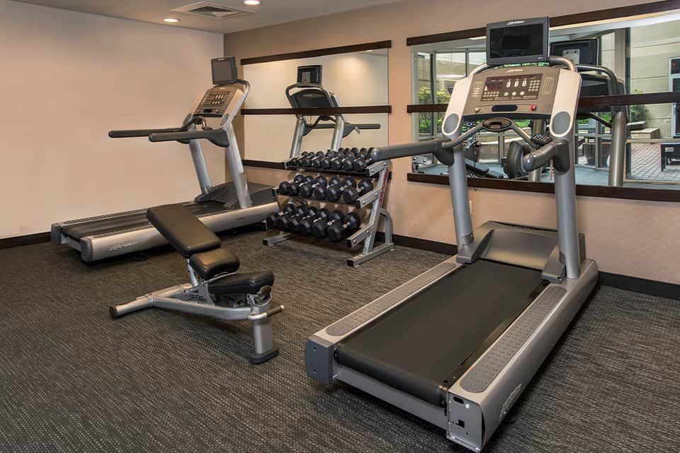 Fitness center with treadmills, exercise bikes, dumbbells, and mirrored walls