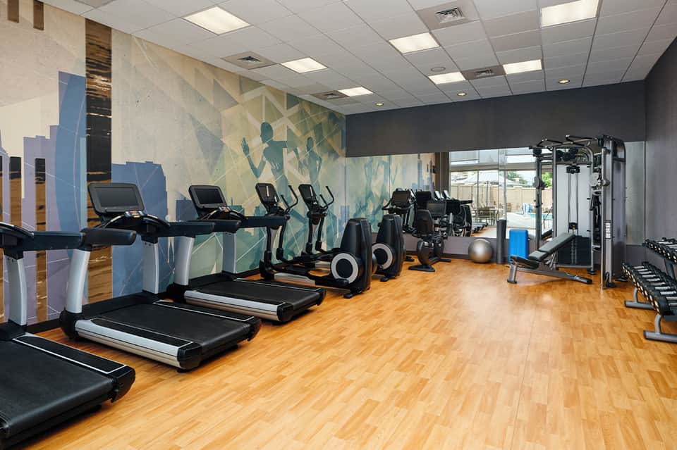 Fitness center with treadmills, exercise bikes, and strength training equipment on wooden flooring