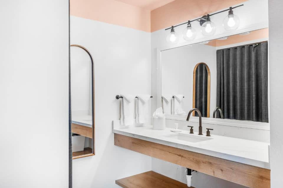 Modern bathroom with white double sink vanity, mirror, and dark shower curtain