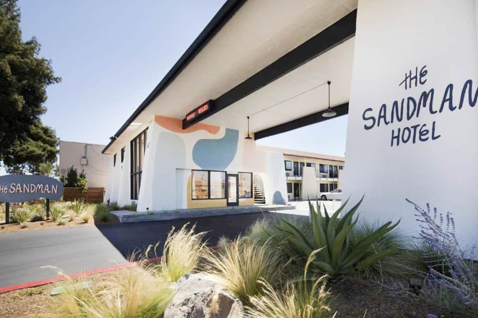 The Sandman Hotel exterior with modern white and beige architecture and desert landscaping
