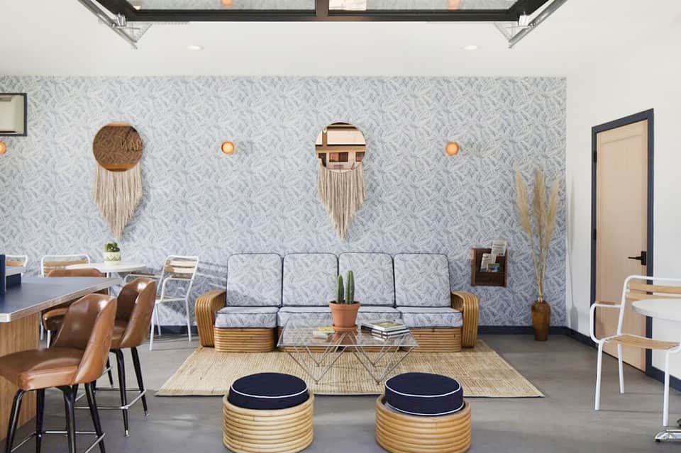 Contemporary resort lobby with patterned wallpaper, woven wall art, modern furniture, and skylight