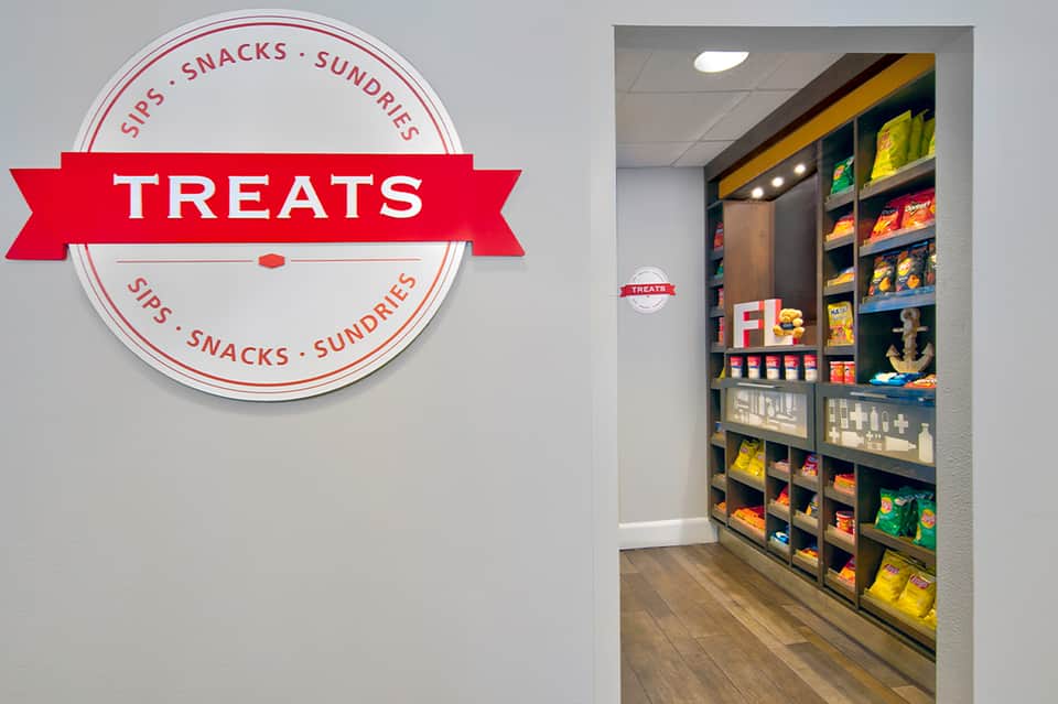 Snack shop interior labeled 'Treats' with shelving displaying chips, candy, and beverages