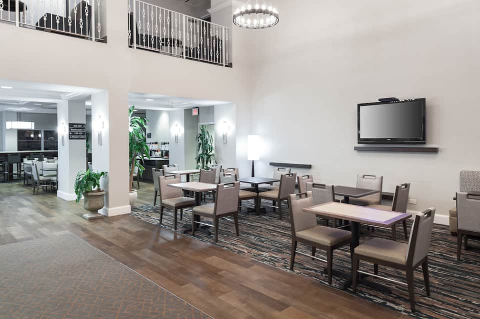 Modern hotel common area with lounge seating, TV, mezzanine level, hardwood flooring, and neutral décor