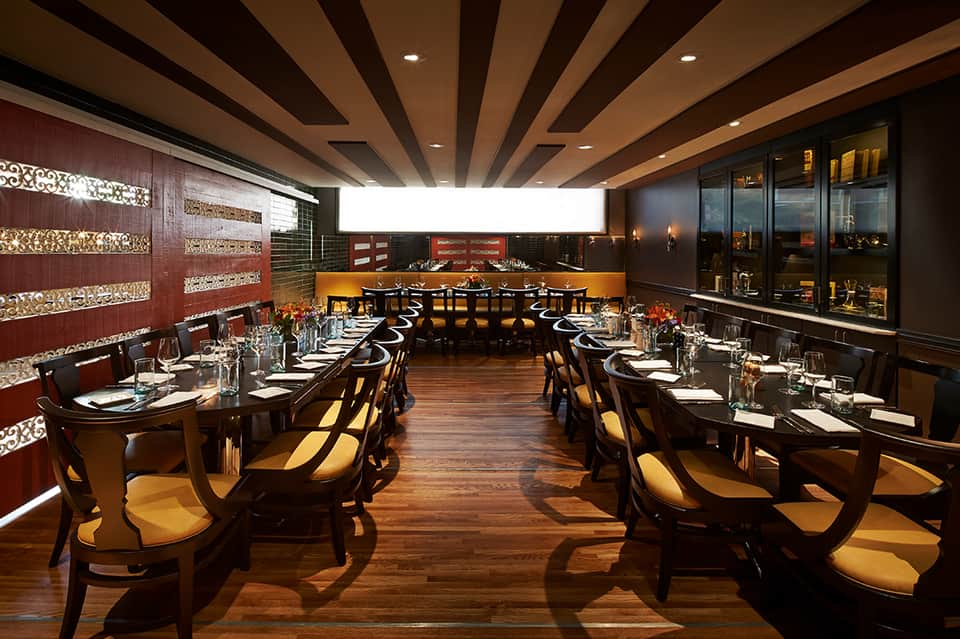 Fine dining restaurant with elegant table settings, wooden beams, and city views