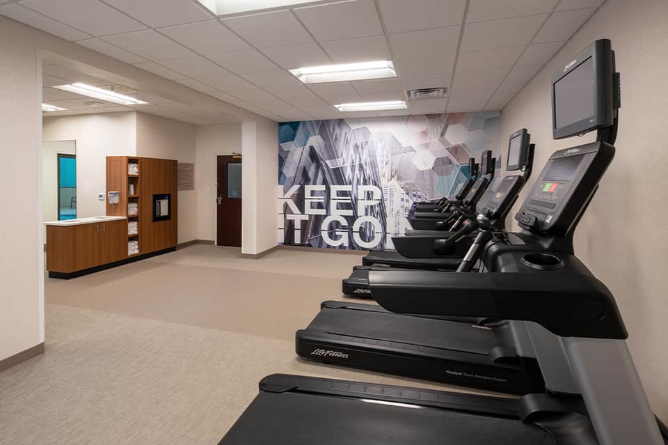 Hotel fitness facility with row of treadmills and motivational wall mural