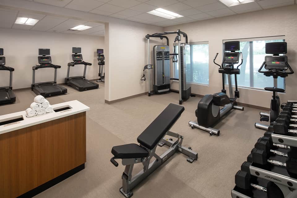 Hotel fitness center with treadmills, exercise bikes, weight equipment, and amenity counter