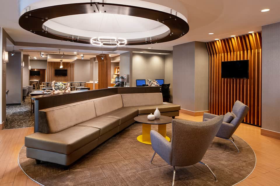Modern hotel lobby lounge with circular ceiling light and tan seating