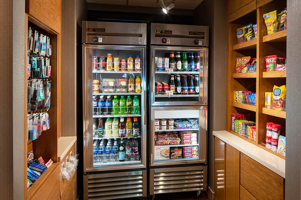 Hotel convenience shop with refrigerated beverage display and snack shelving