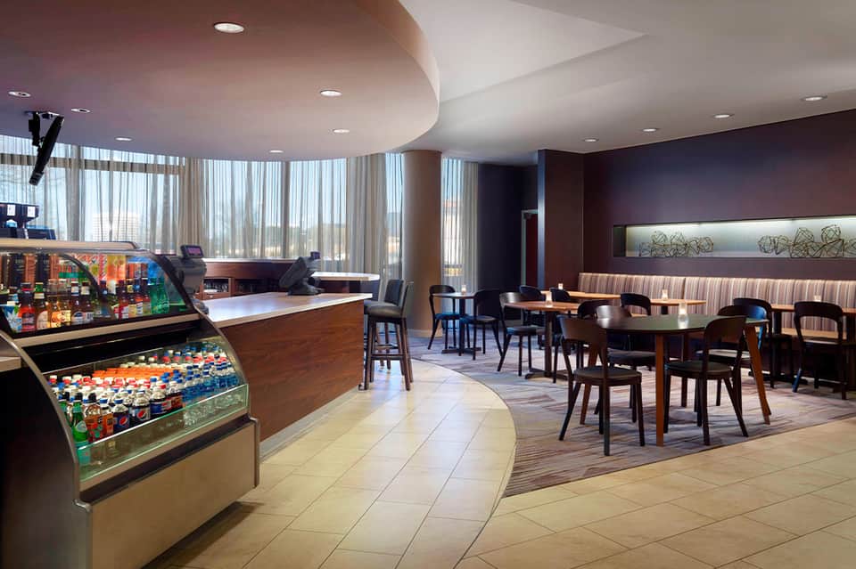 Hotel lounge with snack bar, seating area, large windows, and modern furnishings