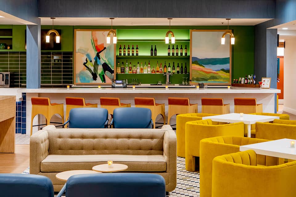 Contemporary hotel bar and lounge with green accent walls, colorful chairs, and modern design