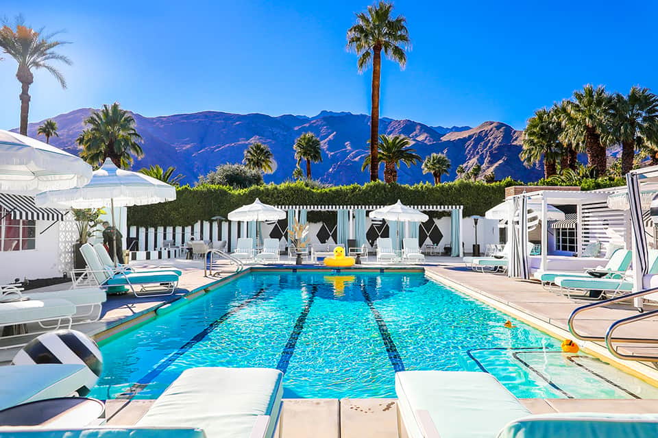 Olympic-style pool with lap lanes, white cabanas, palm trees, and mountain backdrop at resort