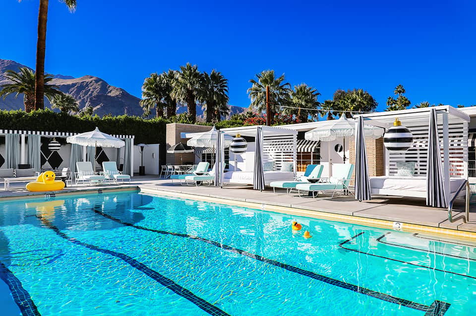 Olympic-style lap pool with lane dividers, cabanas, and mountain backdrop under blue sky